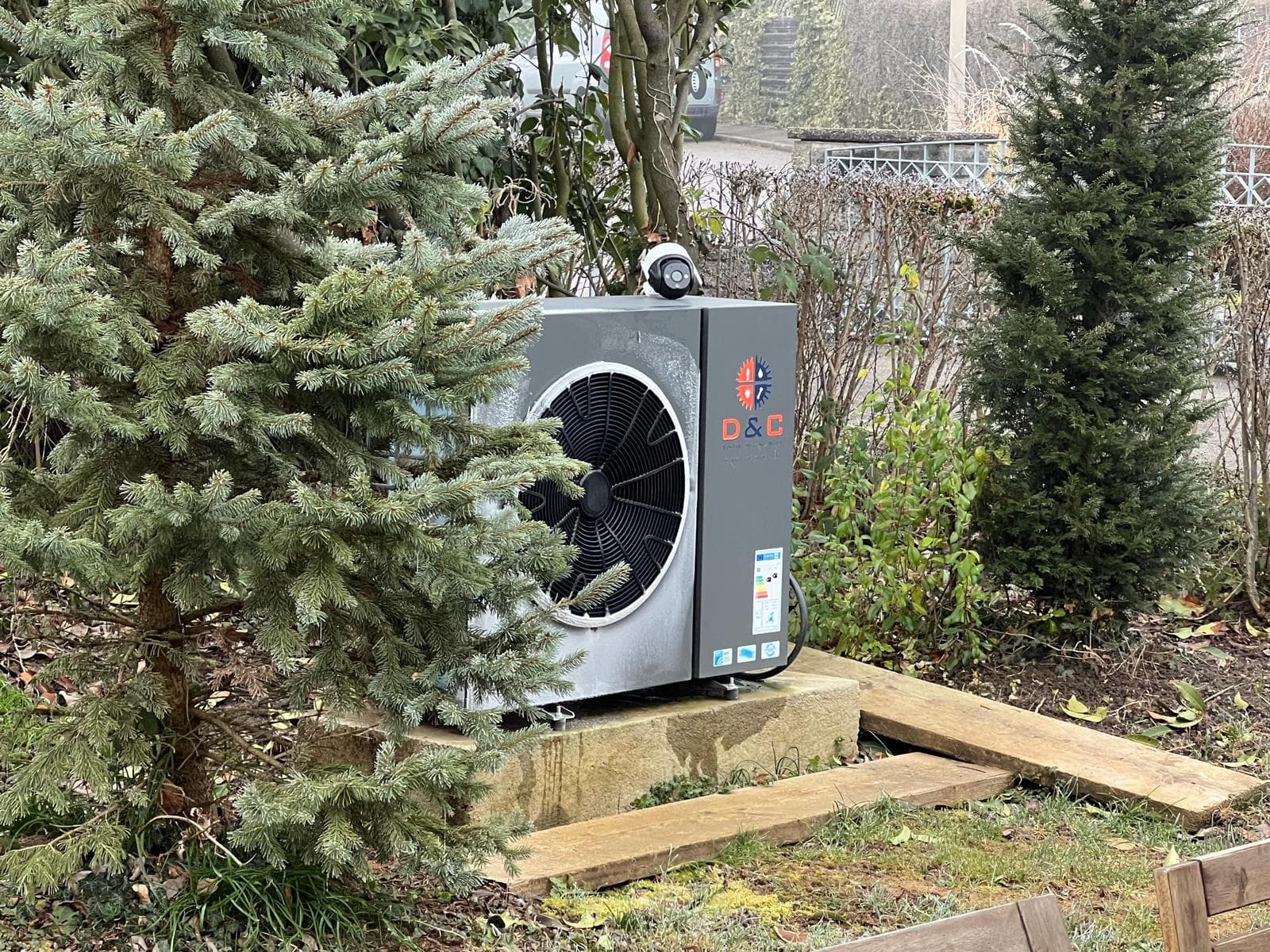 D&C Wärmepumpe zwischen Bäumen im Außenbereich